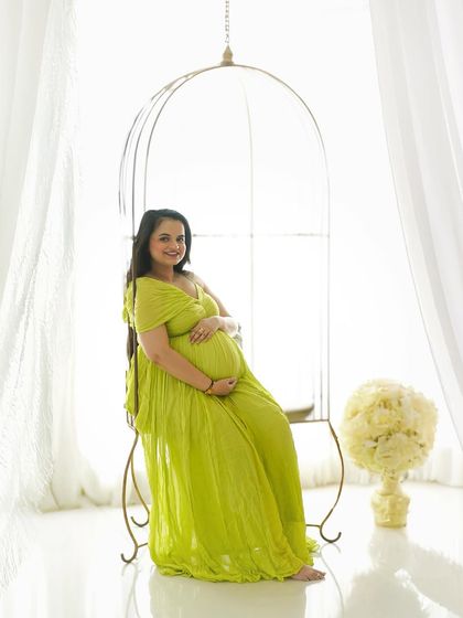 A radiant solo portrait in a bright lime green gown, seated in our elegant birdcage chair.