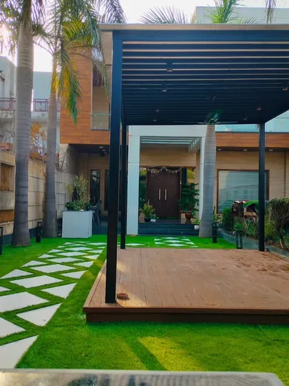A completed front yard landscaping project in Dwarka, New Delhi. Our work extends beyond rooftops to include ground-level gardens, featuring custom pathways and durable wooden decking for pergolas.