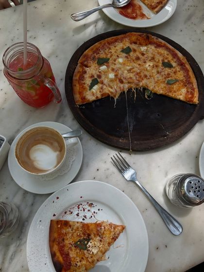 A flatlay of a pizza and coffee lunch with friends, capturing the joy of a shared meal.