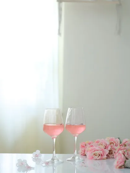 A bright, high-key photograph of two glasses of rosé wine with pink roses. This minimalist style feels clean, elegant, and modern.