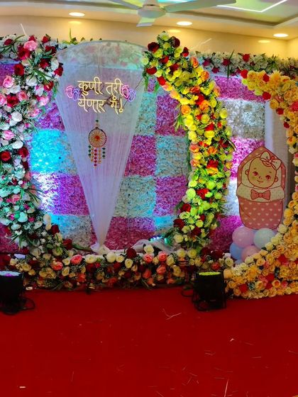The complete stage view of our Dohale Jevan decoration. It showcases the checkered floral wall, a floral moon element, and baby cutouts, creating a vibrant and festive look.