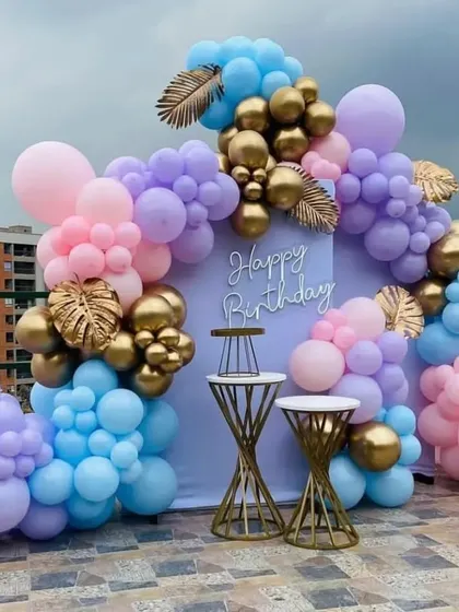 We can turn any space into a stunning party venue, like this building terrace. For this celebration, we built a beautiful backdrop with a custom "Happy Birthday" sign, framed by an organic balloon arch in pastel and gold tones, complete with elegant cake stands.