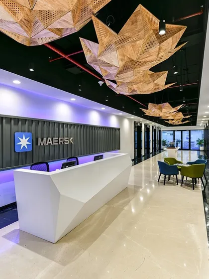 For Maersk's office, we designed a reception area with a dramatic, geometric desk and custom-designed, origami-like light fixtures made of wood veneer. The design reflects the global logistics leader's precision and scale.