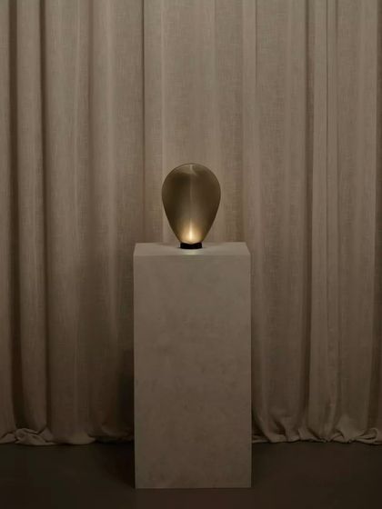 A single bronze glass Solace lamp creates an intimate and moody atmosphere, its form almost disappearing into the shadows until illuminated.
