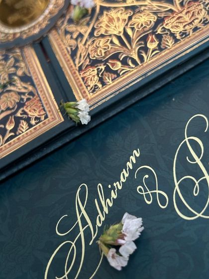 A close-up of the elegant gold script and subtle embossed pattern on the deep blue invitation.