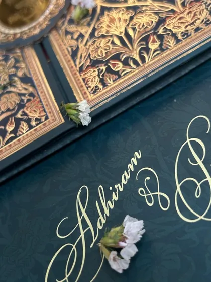 A close-up of the elegant gold script and subtle embossed pattern on the deep blue invitation.