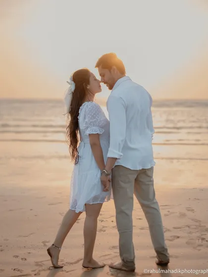 A classic sunset silhouette on the beach. The couple is about to kiss, framed against the glowing sky and sea. This is a timeless and romantic shot for any pre-wedding gallery.