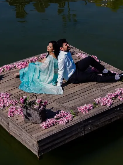 A unique and serene pre-wedding photo of the couple on a floating wooden raft, surrounded by flowers. This setup creates a truly one-of-a-kind memory.