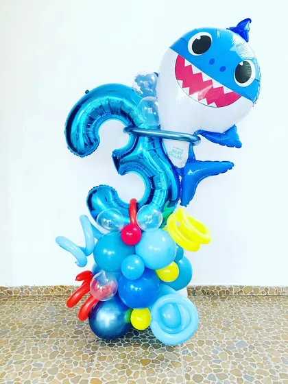 A fun Baby Shark balloon bouquet. This arrangement features a large Baby Shark foil balloon on top of a blue balloon pillar with a number '3' foil balloon.