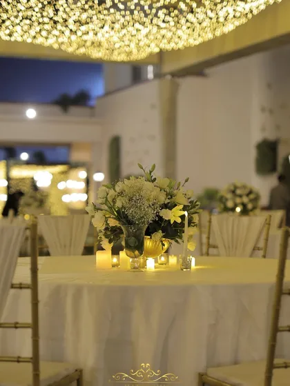 A close-up of a candlelit centerpiece with white flowers. The soft glow adds to the romantic and intimate atmosphere of the evening.