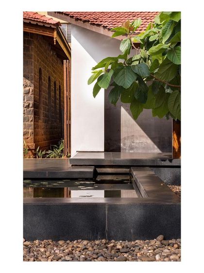 A detail where the new black stone water channel meets the old stone wall of the colonial building. This junction highlights the careful dialogue between our intervention and the original structure.