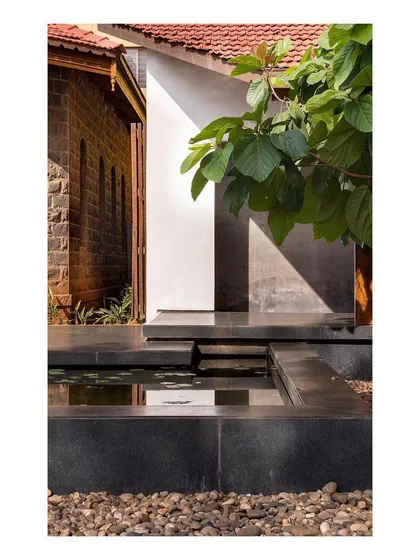 A detail where the new black stone water channel meets the old stone wall of the colonial building. This junction highlights the careful dialogue between our intervention and the original structure.