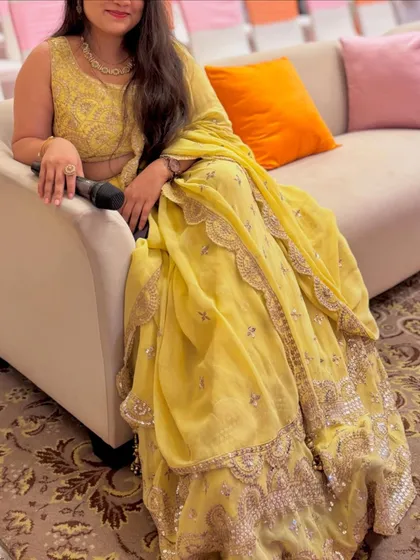 A happy client relaxing at an event in a beautiful yellow embroidered outfit. Renting makes enjoying special occasions so much easier.