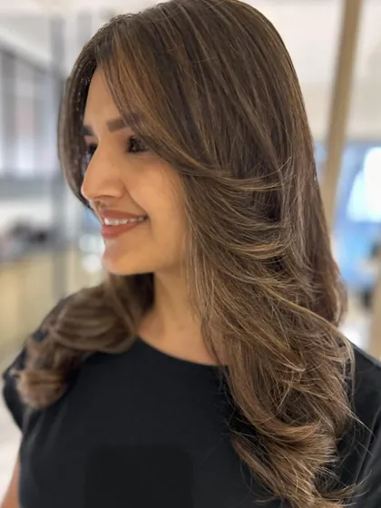 A three-tone hair color paired with curtain bangs and face-framing layers. The color enhances the haircut, creating a stylish, blended look.