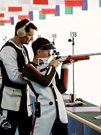 Precision meets guidance. A coach provides subtle adjustments to a young shooter's stance, a critical part of our personalized training approach.