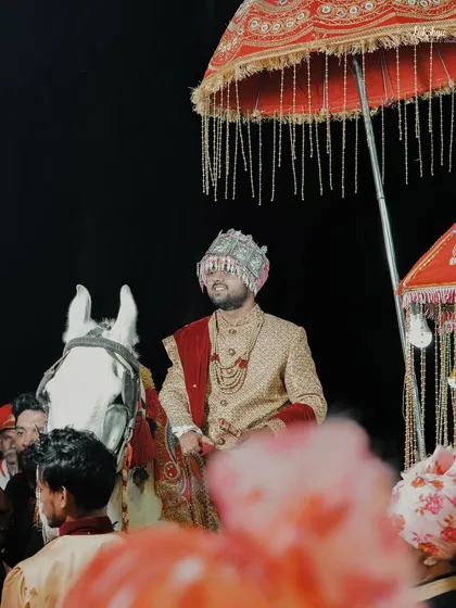 The groom's grand entrance on a white horse, complete with a traditional umbrella. This shot captures the excitement and tradition of the baraat procession.