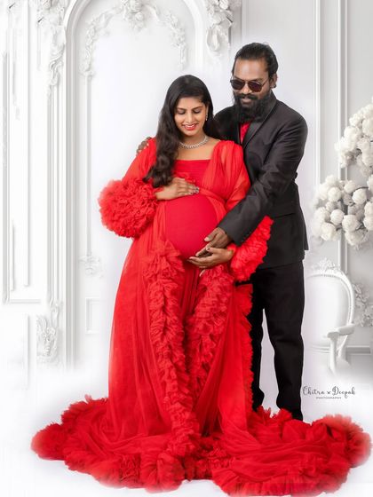 A glamorous couple's portrait against a classic white backdrop. The bold red gown makes a stunning statement.