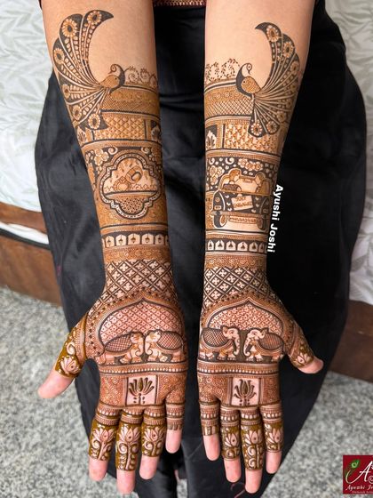 A slightly different angle of the engagement mehendi, highlighting the intricate grid work and the graceful peacock designs on the upper arms.