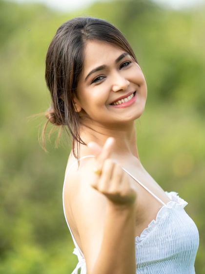 A cute and trendy pose with a finger heart. This shows the model's ability to connect with the camera in a fun and modern way.