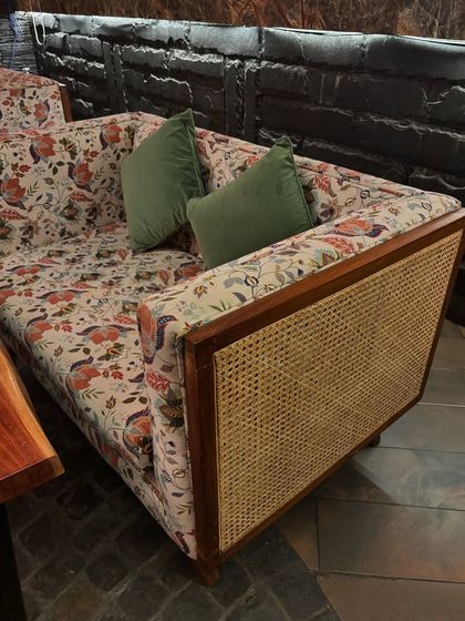 Adding some florals to the fall season. This unique sofa combines a sturdy teakwood frame with rattan cane detailing on the sides and is upholstered in a vibrant floral print, bringing a touch of bohemian charm to the space.
