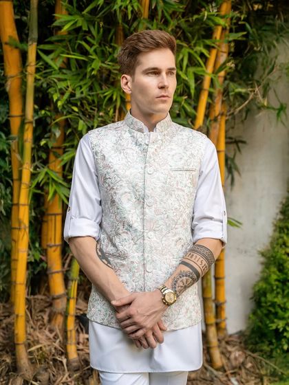 The pastel floral vest against a natural backdrop. The subtle colors and intricate embroidery are inspired by nature, creating a look that is both fresh and elegant.