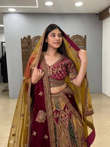 The mustard yellow dupatta adds a beautiful pop of color to the rich velvet of this bridal outfit.