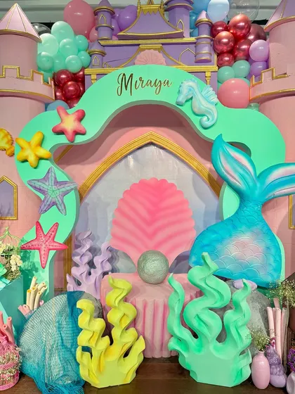 Welcome to an under-the-sea kingdom. We built a magical mermaid castle entrance, complete with a giant clamshell, shimmering mermaid tail, and colorful coral props.