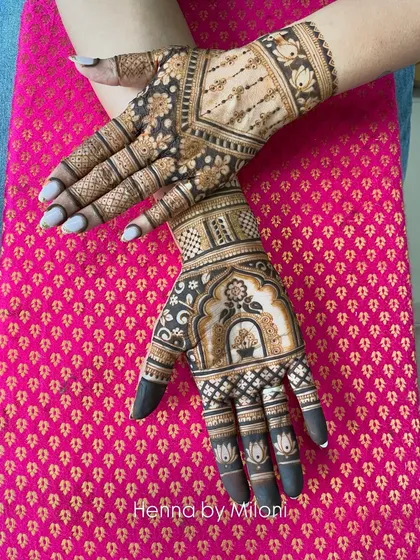 A unique bridal mehendi design with a focus on symmetry and negative space. The central kalash motif is surrounded by delicate patterns and bold, dark fills.