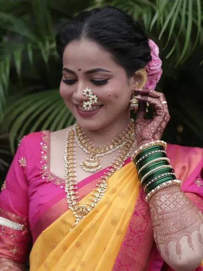A beautiful portrait of the bride in her yellow and pink wedding saree, adorned with a traditional nath and green bangles.