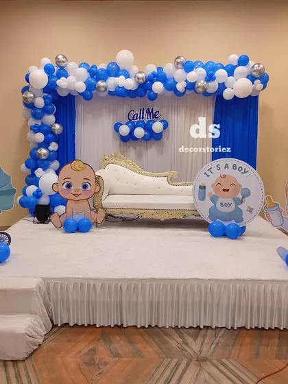 A complete stage setup we designed for a baby boy's baptism ceremony in a banquet hall. The decor includes a blue and white balloon arch, drapery, and cute cartoon cutouts to create a joyful and celebratory theme.