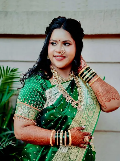 The rich green of her saree and the intricate gold jewelry are the perfect frame for her glowing makeup. This is a classic and regal Maharashtrian bridal look.