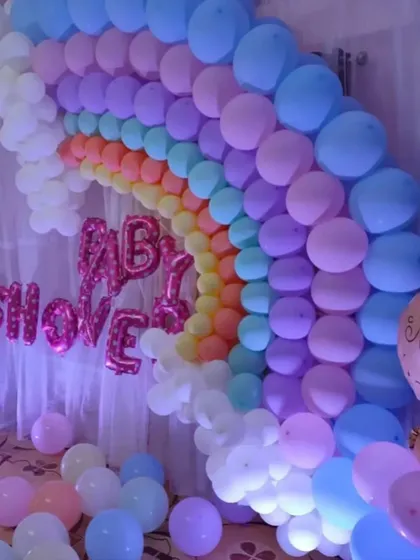 Another angle of the pastel rainbow balloon arch, showing how it can transform a room for a baby shower. The soft colors and cloud-like white balloons at the base create a dreamy effect.