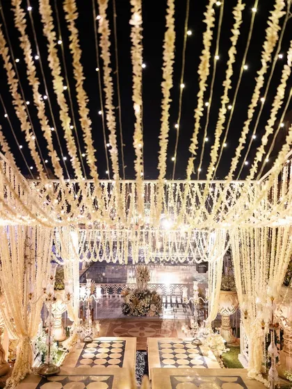A view from the stage, looking out at the surreal, all-white setting. The ceiling was a dense canopy of hanging floral strings and fairy lights, creating a dreamlike atmosphere.