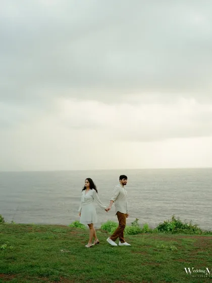 A creative shot of the couple on a cliff overlooking the sea in Goa. The composition creates a sense of anticipation and adventure, perfect for a pre-wedding story.