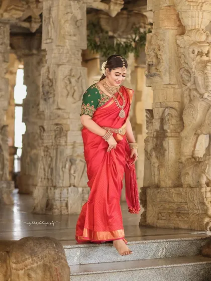The ancient stone pillars of a temple provide a powerful and serene backdrop for bridal portraits. This image captures a candid moment of happiness, blending the bride's modern joy with the timeless sanctity of the location.