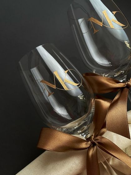 A close-up of the monogrammed wine glasses. The design is modern and elegant, making it a popular choice for wedding and anniversary gifts.
