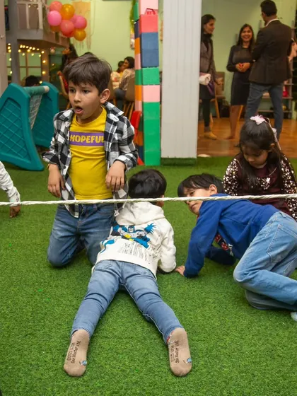 A group of kids carefully making their way under the limbo rope.