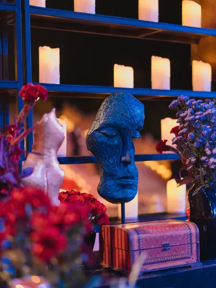 A close-up of an art-inspired decor piece, a sculptural face bust, set against a backdrop of candles, adding a touch of curated artistry to the event.