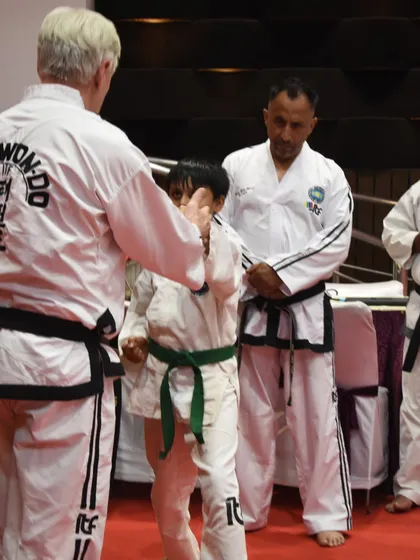 A Grandmaster provides hands-on correction to a young student, an invaluable experience for the child.