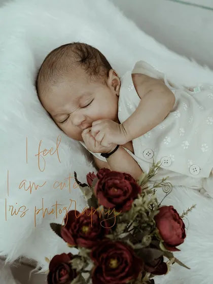 A peaceful and delicate newborn portrait of a baby sleeping soundly on a soft, white fur blanket. The simple setup with a touch of floral decoration emphasizes the innocence and beauty of a newborn's first days.