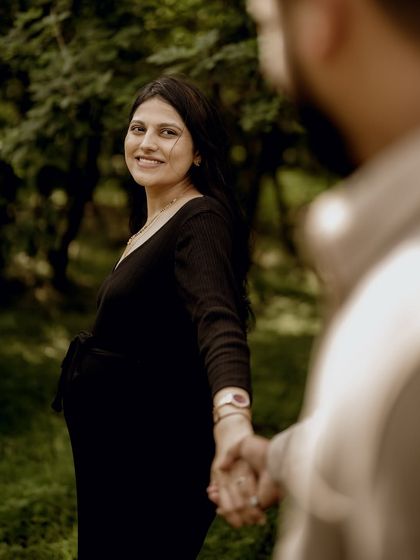 A classic "follow me" shot, with her looking back over her shoulder with a beautiful smile. The lush green forest provides a stunning backdrop.