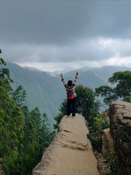 A trekker standing on the edge of Dolphin's Nose, with a stunning view of the valley.