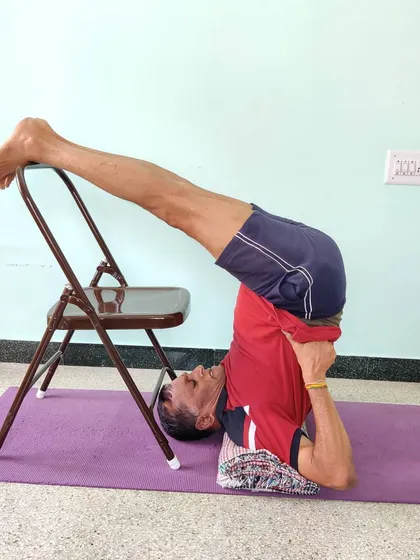 Ardha Halasana (Half Plow Pose) with legs resting on a chair. This is an excellent preparation for full Halasana and Sarvangasana, teaching the body the correct alignment.
