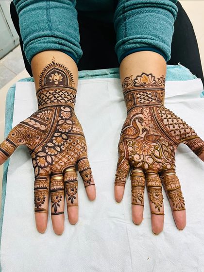 This image shows two different but complementary designs for a bride. One hand features a peacock, and the other a lotus dome, demonstrating how we can incorporate multiple favorite motifs into a single bridal set.