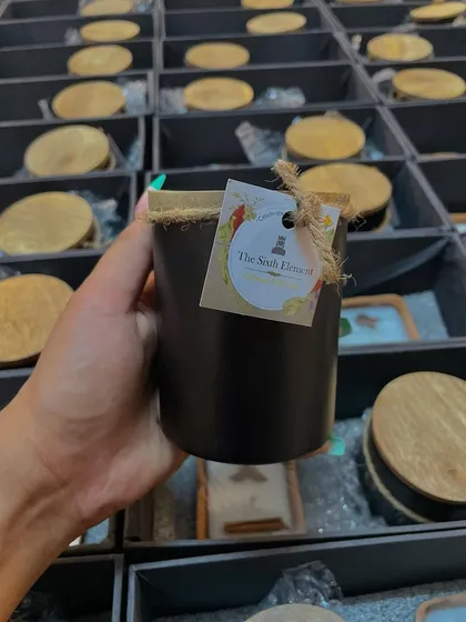 A handheld view of our black jar candle, customized for a corporate client. The rustic twine and personalized tag add a handcrafted feel to the gift, making it feel more personal and less mass-produced.