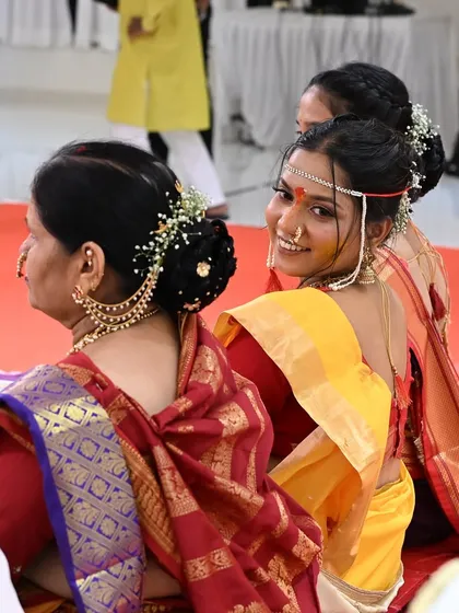 A candid shot of the bride during her Punyawachan ceremony. The focus is on her elegant hairstyle, adorned with fresh flowers and a traditional hair accessory.