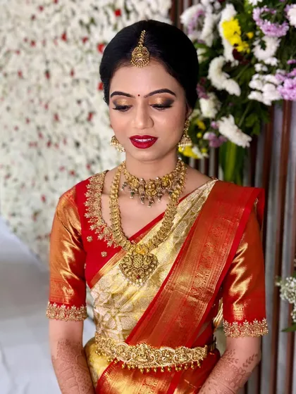 A classic South Indian bridal look is timeless. For Prakruthi's Muhurtham, we chose a bold red lip and shimmering gold eyeshadow to perfectly complement her traditional red and gold Kanjivaram saree and temple jewellery.