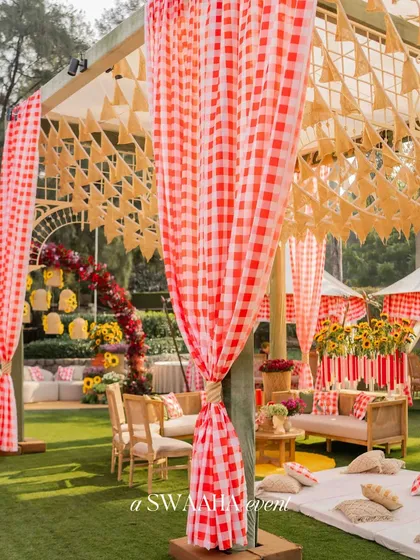 A whimsical countryside picnic theme for a baby shower, with red-and-white checkered drapes and tents creating a nostalgic and charming atmosphere.