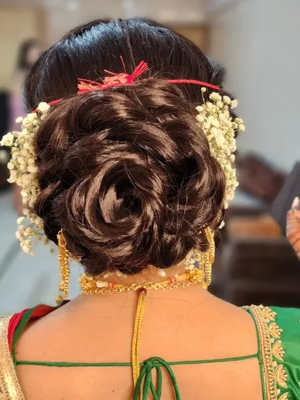 An elegant and luminous rosette bun, intricately styled and adorned with fresh baby's breath for a timeless bridal look.