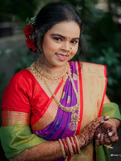 A close-up portrait of the bride, showcasing her beautiful smile and the traditional Maharashtrian nath. The photo captures her joy and the fine details of her jewelry.